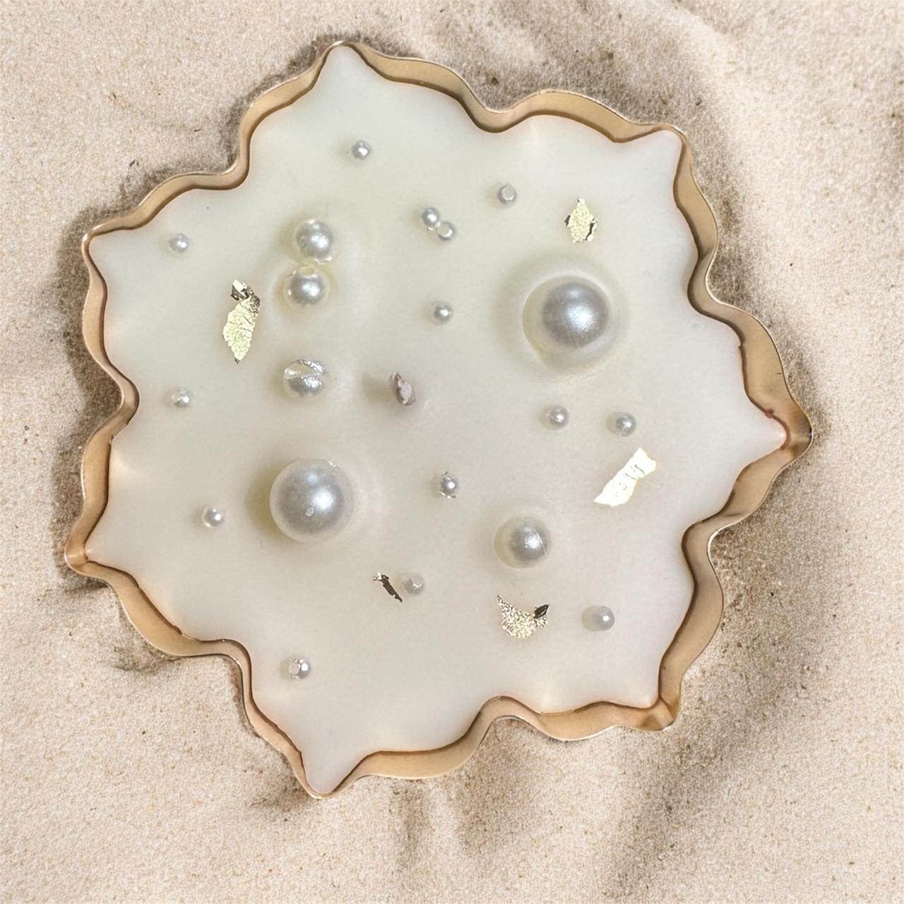 Studio Veeha pearl and gold leaf luxury candle presented on sand